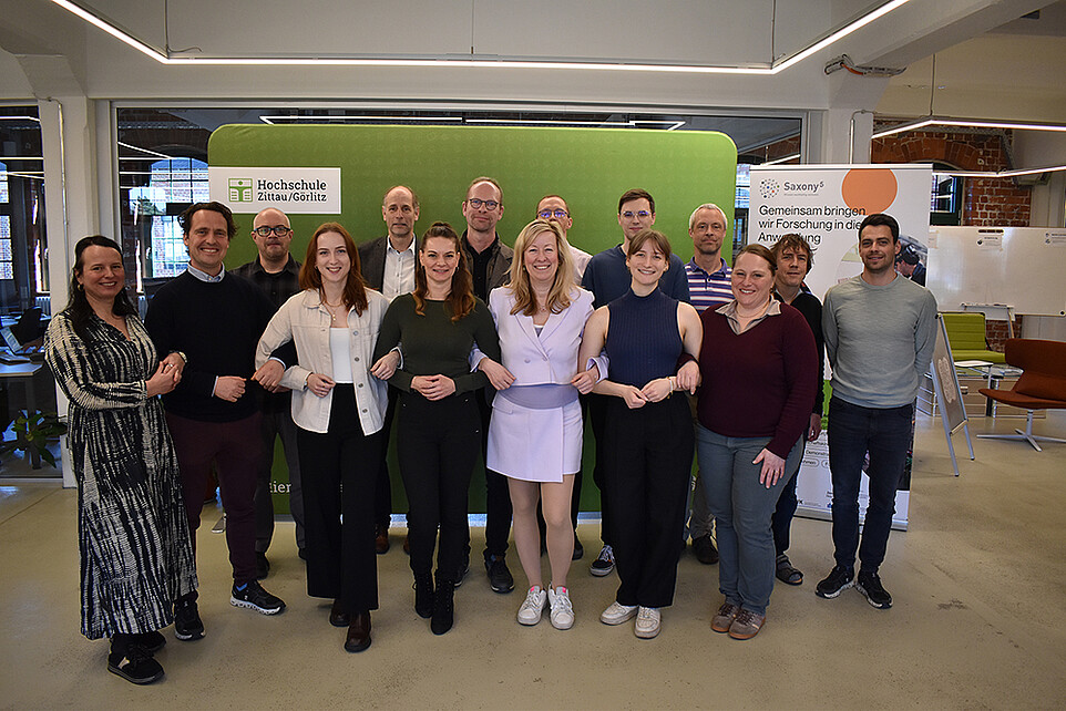 Gruppenbild der Teilnehmenden vor einer grünen Pressewand.