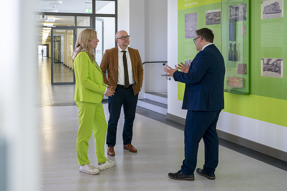 Rektor, Prorektorin und Herr Denk stehen im Flur von Haus eins und unterhalten sich.