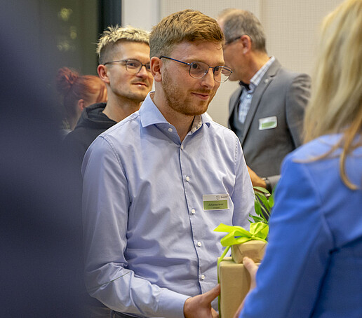 Ein Preisträger hält ein Geschenk in den Händen.