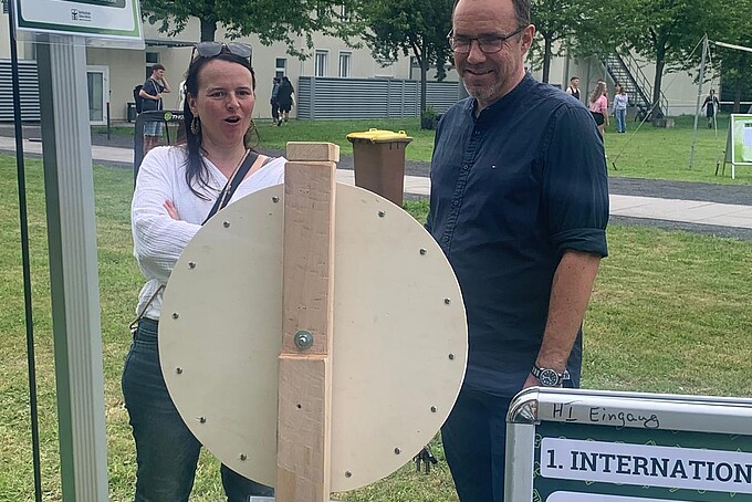 Zwei Mitarbeitende stehen vor dem Glücksrad und unterhalten sich.