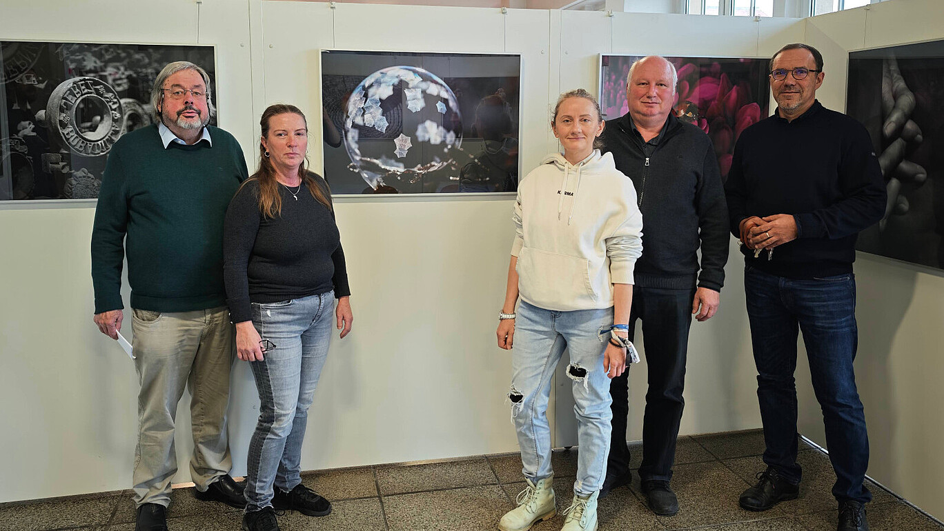 Vor dem Siegerbild steht die Jury und lächelt in die Kamera.