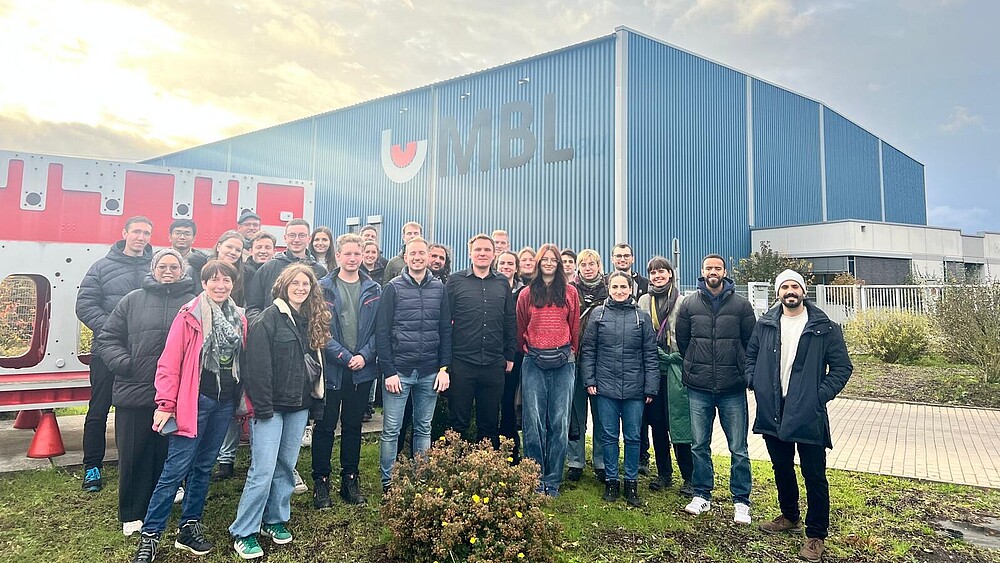 Eine Gruppe Studierender steht auf dem Firmengelände einer Fabrik.