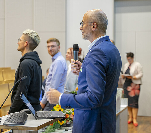 Die Preisträger des Fördervereins stehen nebeneinander vor dem Publikum. Prof. Maiwald spricht in ein Mikrofon.