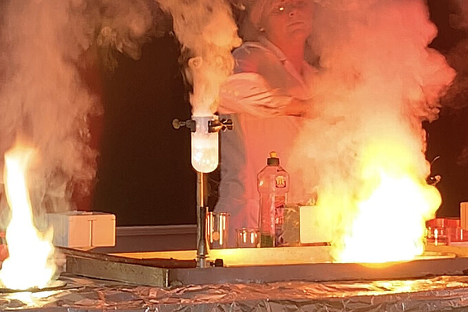 Eine Labormitarbeiterin betreut im Labor einen Versuch mit Feuer.