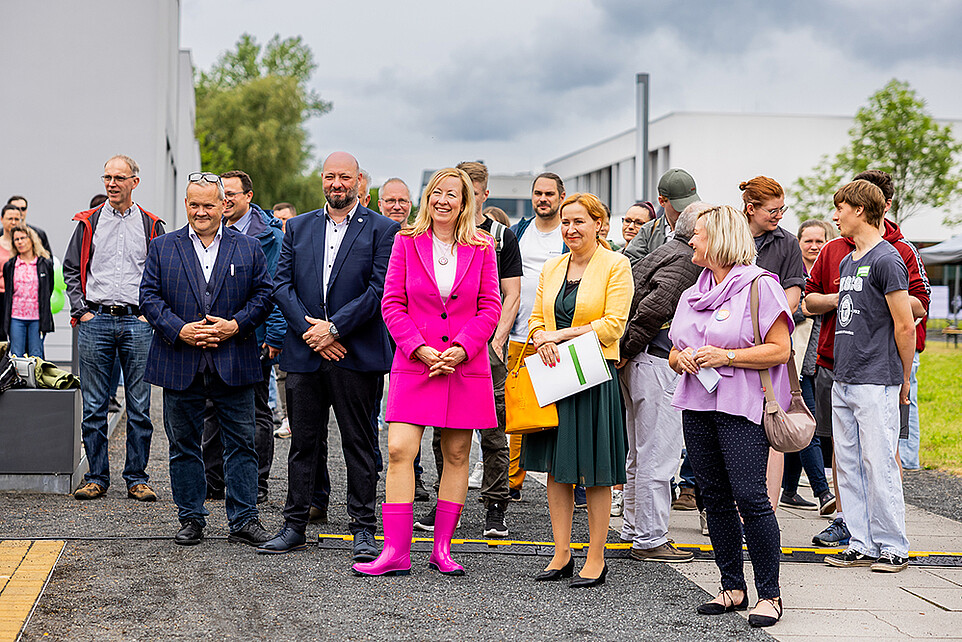 Gäste der Einweihung unterhalten sich vor dem grünen Klassenzimmer.